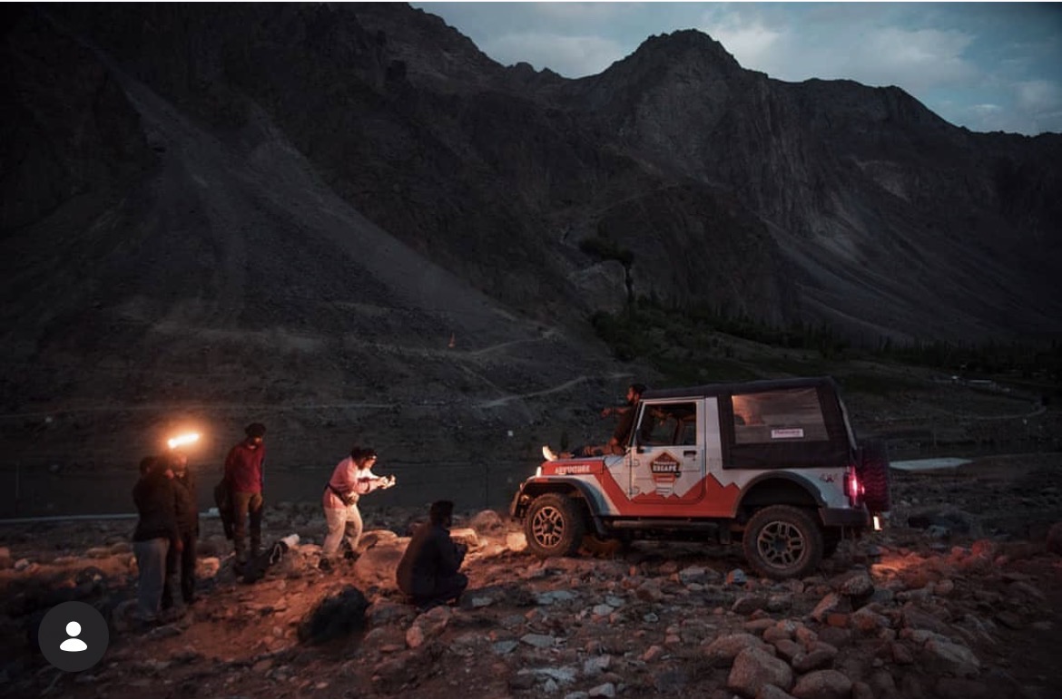 Crew lighting a Mahindra Thar on a Himalayan riverbed at dusk